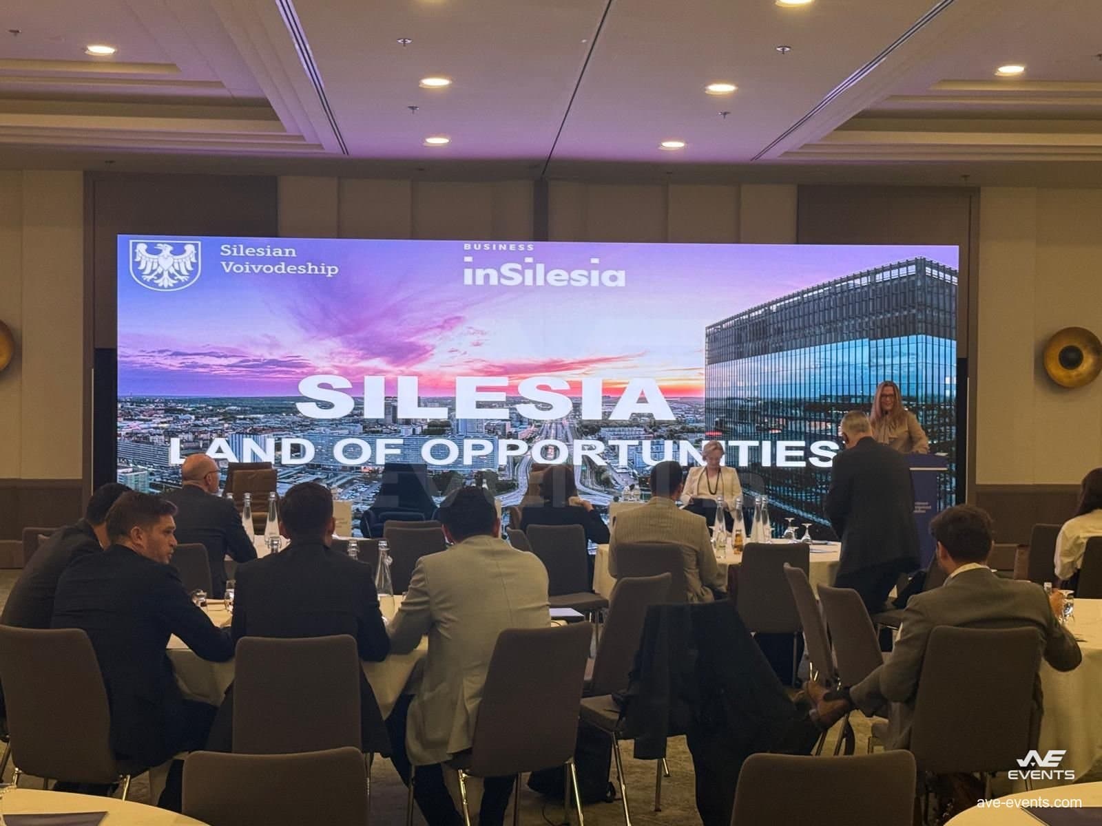 IME Frankfurt 2025: Delegierte an runden Tischen während einer Sitzung, mit der Präsentation auf der LED-Wand