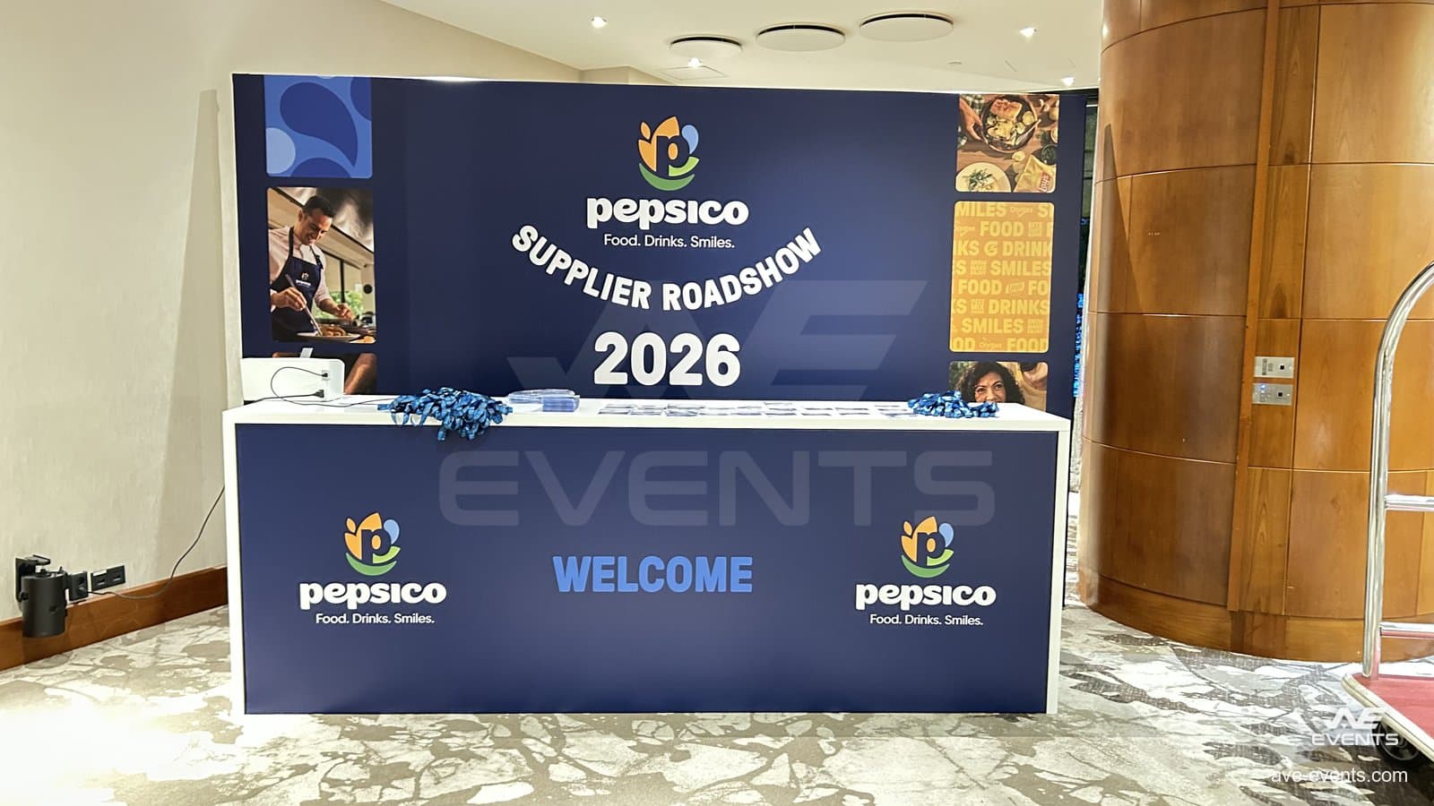 PepsiCo Supplier Roadshow 2026: le bureau d'accueil habillé à l'entrée, avec les badges des délégués disposés